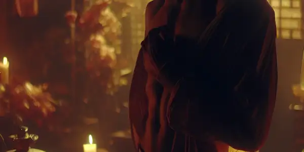 A dimly lit room with vintage decor, featuring a charismatic male silhouette and intimate romantic elements.